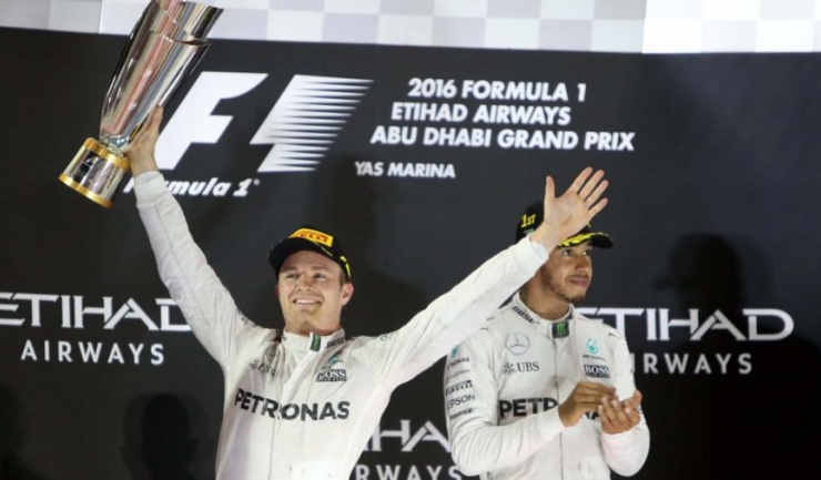 Nico Rosberg ridică trofeul cuvenit campionului mondial de Formula 1, în timp ce Lewis Hamilton nu-și poate ascunde dezamăgirea